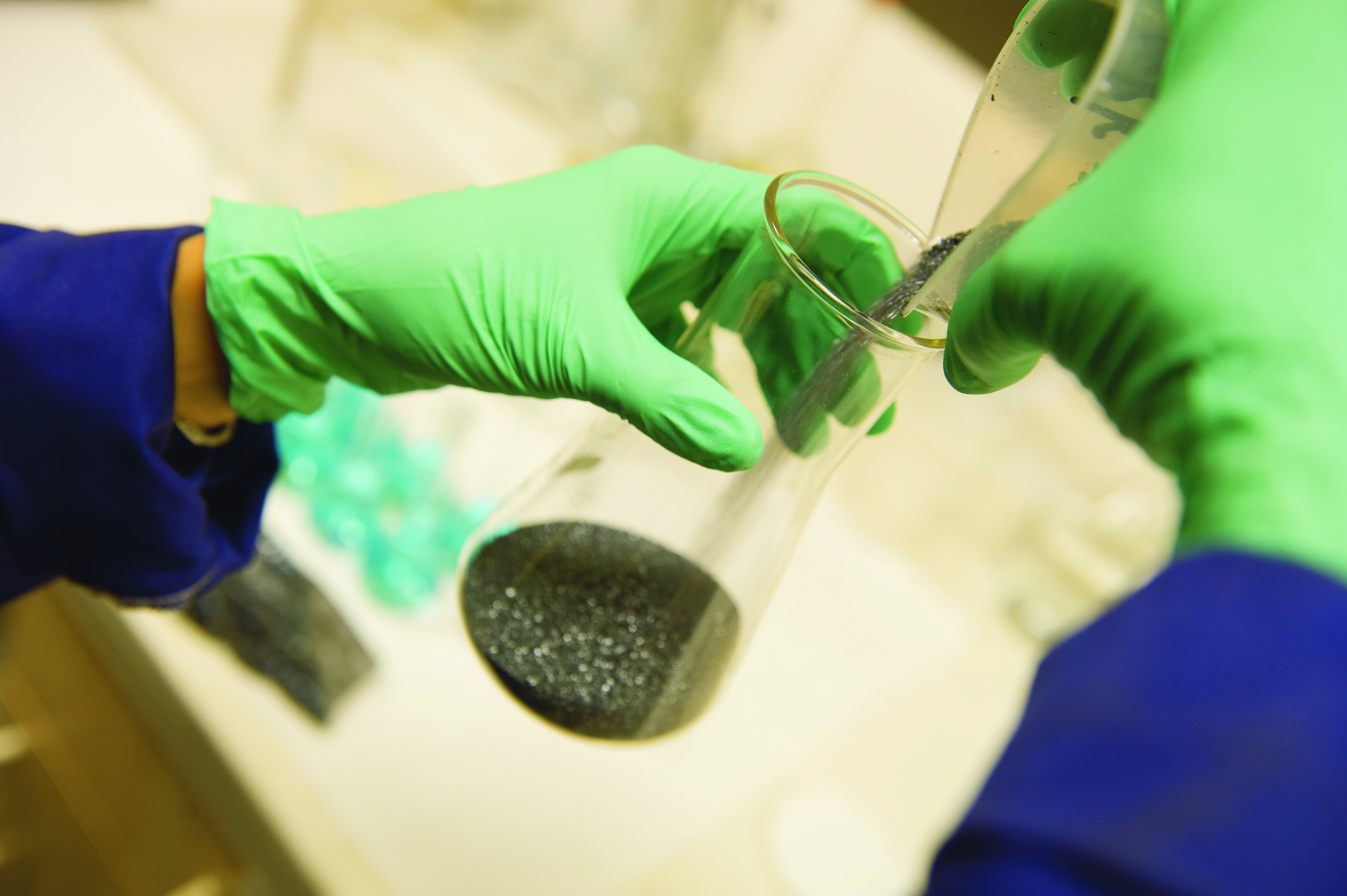 Close up image of gloved hands mixing chemicals